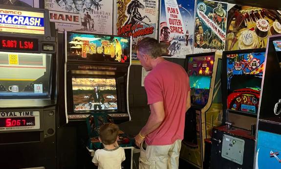 A dad and son playing an old arcade game