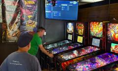 A man watching another man playing an arcade game