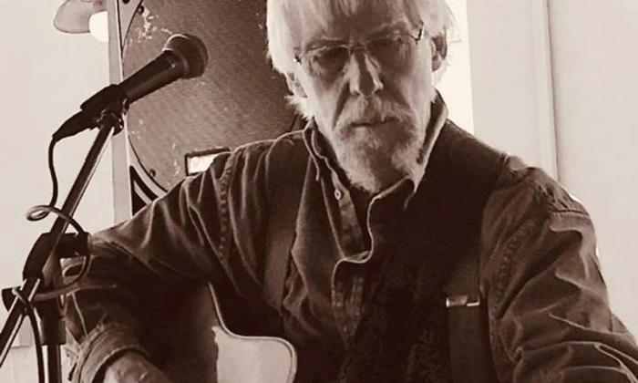 Songwriter Bob Patterson tuning his twelve-string guitar