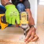 The hands of a handyman as he fastens a floor to the subfloor