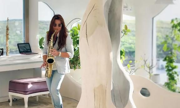 Karina, in washed out jeans and a pale blue blazer, plays alto sax on a lovely deck