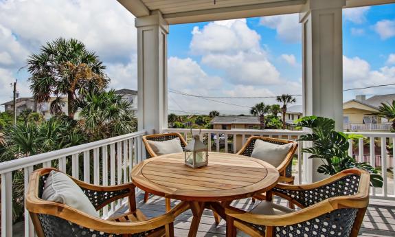 This second-story deck near the beach has a teak table and four matching chairs and a great view