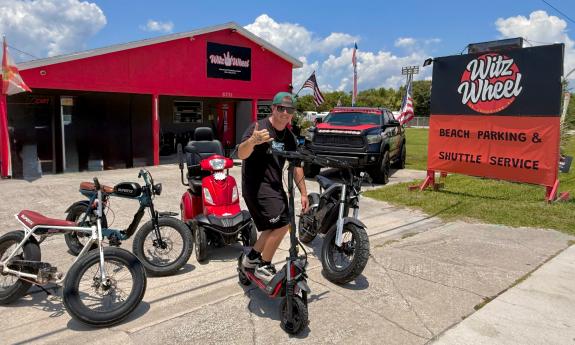 A man on a scooter, standing with several e-vehicles in front of Witz Wheel